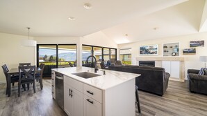 Een moderne keuken met een groot kookeiland, een eethoek met stoelen, en een woonkamer met een bank.