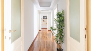 A hallway with wooden flooring, white walls, and a potted plant. - The dreamer house design (Roma)