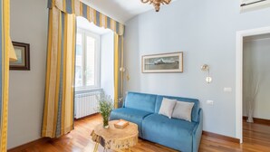 A room with a blue sofa, a round wooden table, a chandelier, and a framed picture on the wall. - The dreamer house design (Roma)