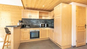 Una cocina compacta con armarios de madera, encimera negra, microondas y estufa.