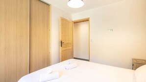 Un dormitorio con una cama grande, un armario de madera y una puerta que da a otra habitación.