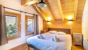 Un dormitorio con cama, dos mesitas de noche, una ventana y techo de madera.