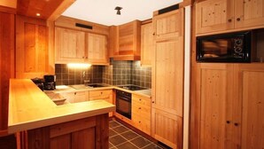 A kitchen with wooden cabinets, a black microwave, and a tiled backsplash.