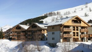 A wooden lodge with multiple balconies and a ski slope in the background.