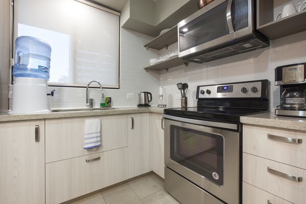 A modern kitchen with stainless steel appliances, white cabinetry, and a water dispenser. - Apartment with GREAT LOCATION, 1 block from the boardwalk (La Paz)