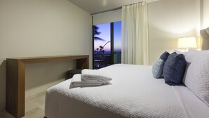 A hotel room with a large bed, a nightstand, a lamp, and a view of the city at dusk. - Apartment with GREAT LOCATION, 1 block from the boardwalk (La Paz)