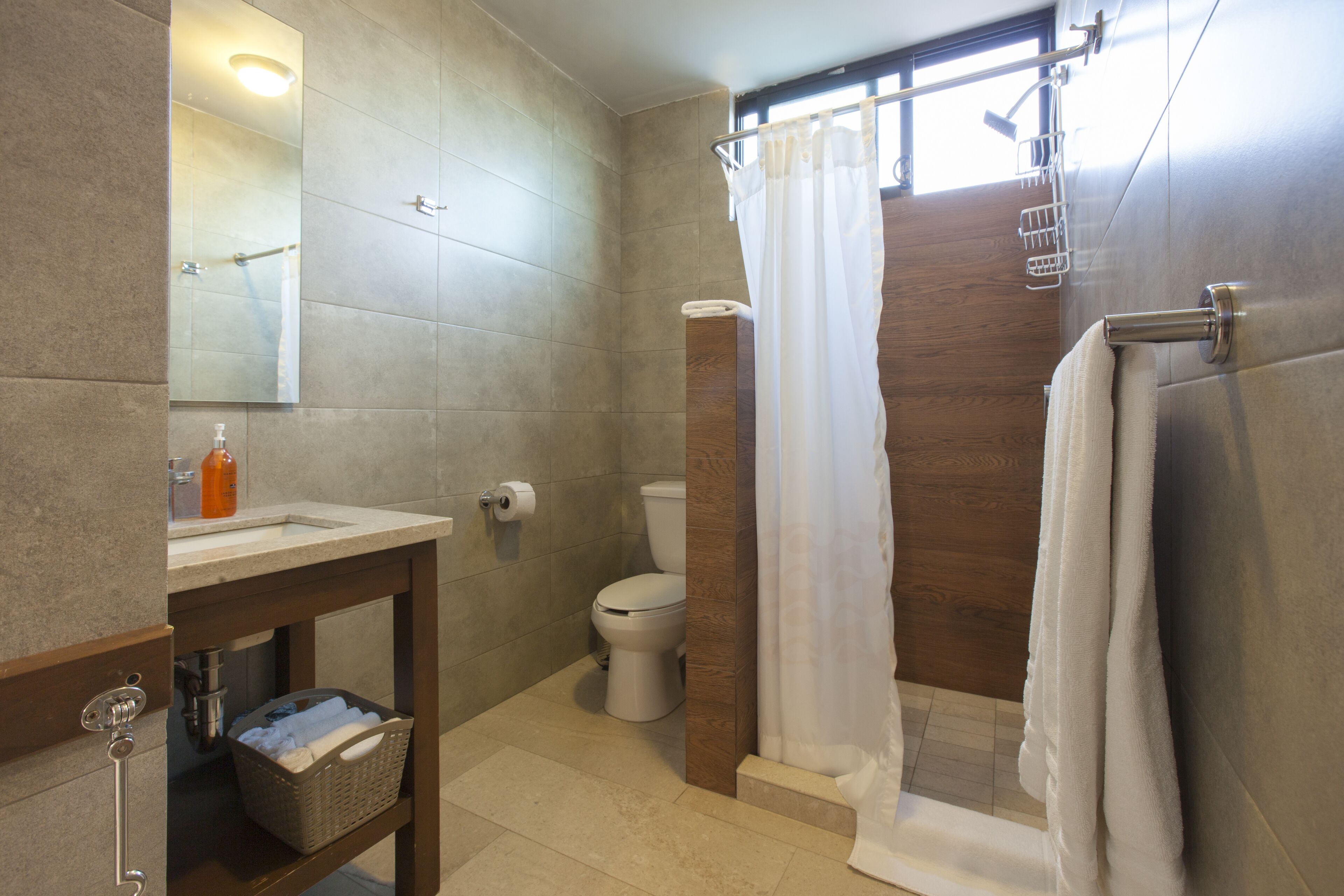 Un baño moderno con lavamanos, inodoro y zona de ducha.