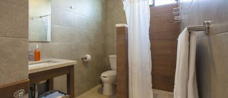 Un baño moderno con lavamanos, inodoro y zona de ducha.