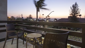 A balcony with wicker chairs and a small round table, overlooking a sunset with palm trees and buildings in the background. - Apartment with GREAT LOCATION, 1 block from the boardwalk (La Paz)