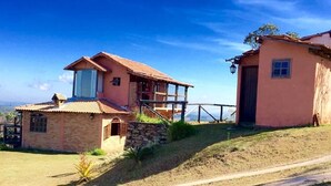 A two-story house with a balcony, a stone foundation, and a dirt path leading to the entrance. - White Mountain (Conceição da Ibitipoca)