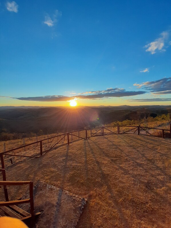 A sunset view from a fenced area with a wooden bench. - White Mountain (Conceição da Ibitipoca)