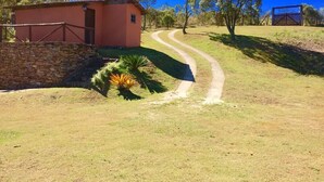 A rural property with a small pink building, a stone wall, and a winding dirt path leading to a gate. - White Mountain (Conceição da Ibitipoca)
