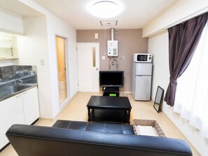 A compact living space with a kitchenette, a flat-screen TV, a microwave, a sofa, and a small table. - ehoraizunkita2jo (Sapporo)