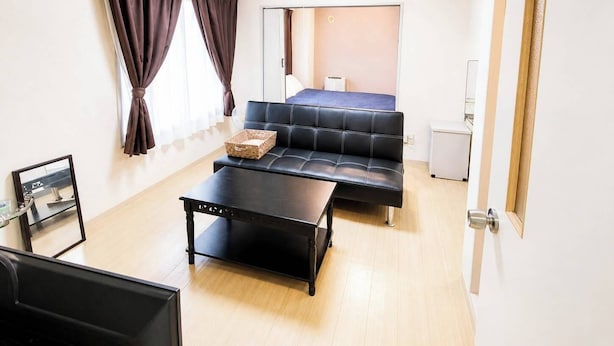 A modern room with a sofa, a small table, and a bed in the background. - Sapporo East Stay minpaku (Sapporo)