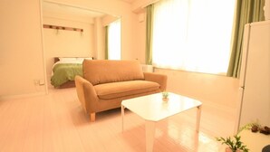 A living room with a beige sofa, a white coffee table, and a small plant on the table. - Sapporo East Stay minpaku (Sapporo)