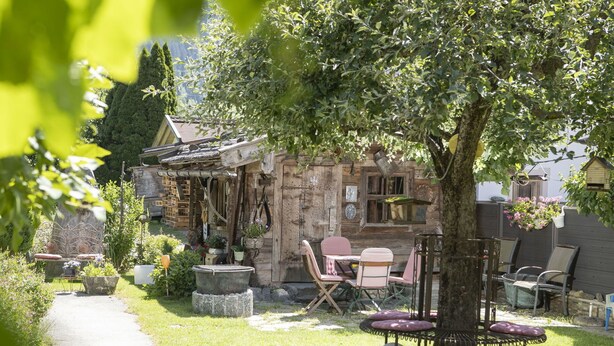 Una cabaña de madera rústica con un sendero de piedra que lleva a una zona de estar con sillas y una mesa.