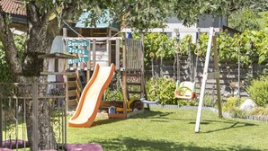 Un parque infantil con tobogán, columpios y una casita de madera.