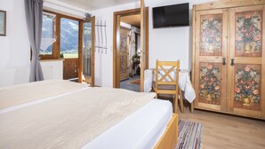 Un dormitorio con cama, una silla, un televisor y una puerta de madera con diseños florales.