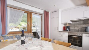 Una cocina moderna con armarios blancos, horno empotrado y ventana con cortinas.