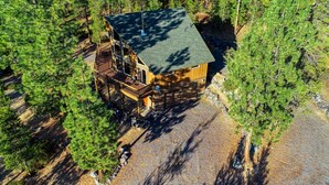 A cabin with a wooden exterior, a deck, and a stone pathway leading to it.