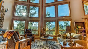 A cozy living room with large windows, a fireplace, and comfortable seating.