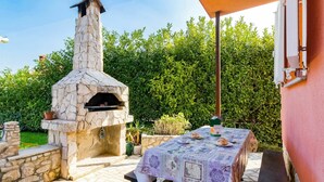 An outdoor patio with a stone-built pizza oven, a table with a patterned tablecloth, and a bench. - Cosy apartment for 4 people with pool, A/C, WIFI, TV and terrace (Pula)