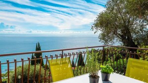 Un balcon avec une table blanche, des chaises jaunes et des plantes en pot.