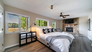 A bedroom with a large bed, a fireplace, and a TV. - LAY Back in the Lake House (Lilburn)