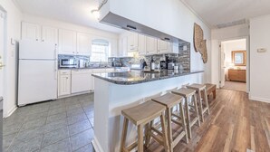 Eine moderne Küche mit weißen Schränken, einer Granit Arbeitsplatte und Holzstühlen.