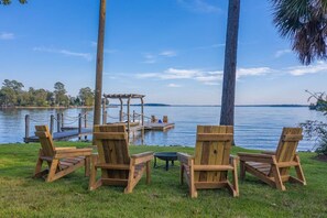 Un entorno junto al lago con sillas de madera y una pequeña mesa, un muelle y un pabellón.