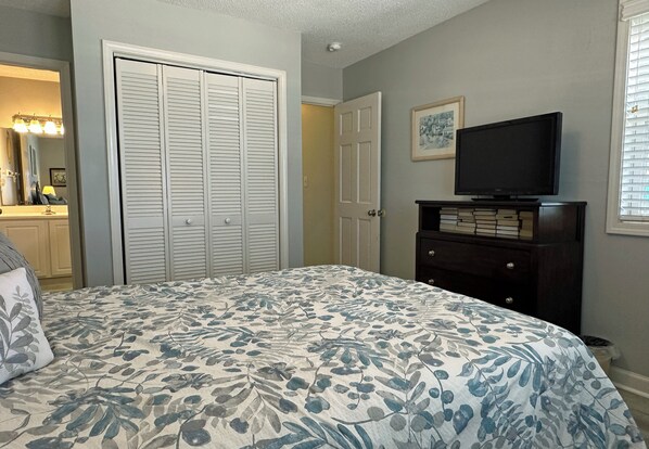 Un dormitorio con cama, cómoda, televisor y armario.