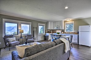 Un espacio habitable pequeño con sofá, sillas, una mesa de comedor y una cocina con refrigerador, microondas y armarios.