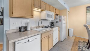 A compact kitchen with wooden cabinets, a white microwave, a coffee maker, a dishwasher, and a refrigerator. - UP TO 50% OFF Lakeside Branson Condo, Incredible view, Pool, Marina (Branson)