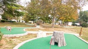 A miniature golf course with a green putting area, a wooden stump obstacle, and a small tunnel. - UP TO 50% OFF Lakeside Branson Condo, Incredible view, Pool, Marina (Branson)