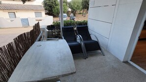 Un balcó amb una taula i dues cadires, una tanca i vista a una zona residencial.