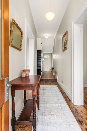 A hallway with a wooden bench, a rug, a mirror, and a door at the end. - TARALGA TERRACES - THE BANK (Taralga)