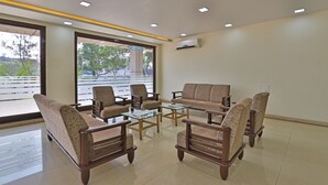 A modern waiting area with a sofa, chairs, and a coffee table. - Utkarsh Hotel (Silvassa)