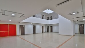 A spacious, multi-level atrium with a high ceiling, skylights, and a red accent wall. - Utkarsh Hotel (Silvassa)
