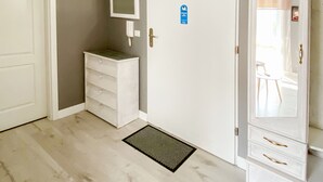 A room with a white door, a white dresser, a small mirror, a blue sign, and a white wardrobe. - Large Terrance (Kolobrzeg)
