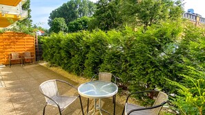 An outdoor patio area with a round glass table and four wicker chairs. - Large Terrance (Kolobrzeg)