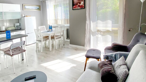 A modern living room with a sofa, a coffee table, and a dining area with chairs and a table. - Large Terrance (Kolobrzeg)