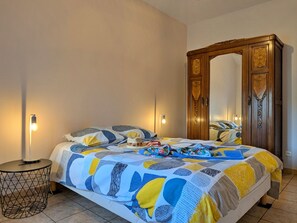 A bedroom with a bed, a wooden wardrobe, a round side table, and two bedside lamps.