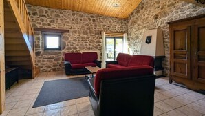 A rustic room with a stone wall, wooden ceiling, and a red sofa.