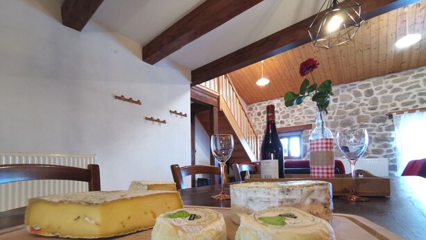 A wooden table with cheese, wine, and glasses.