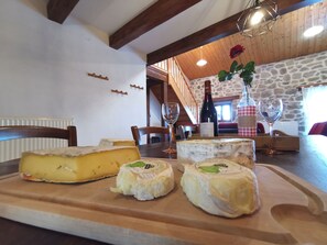 A wooden table with cheese and wine, a stone wall, and a wooden ceiling.