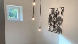 Een trap met een lichtarmatuur en een ingelijst botanisch print op de muur.