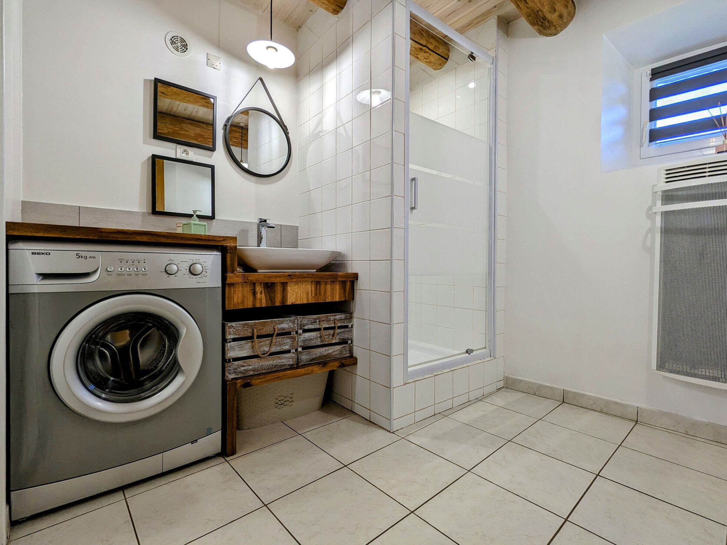 A compact laundry room with a washing machine, a sink, and a shower enclosure.