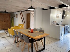 A modern kitchen with a dining area, featuring a wooden table, chairs, and pendant lighting.