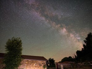 A night sky with stars and the Milky Way over a rural landscape with stone buildings. - Renovated farmhouse with private garden, wood stove and terrace (Saint-Préjet-d'Allier)