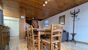 Una mesa de comedor de madera con sillas, un reloj en la pared y un perchero.